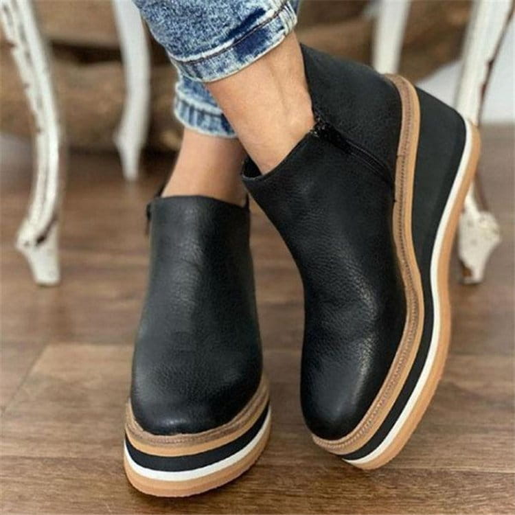 Botines de mujer de cuero negro con suela gruesa en plataforma y cuña, con franjas gruesas superpuestas en color ante y blanco.