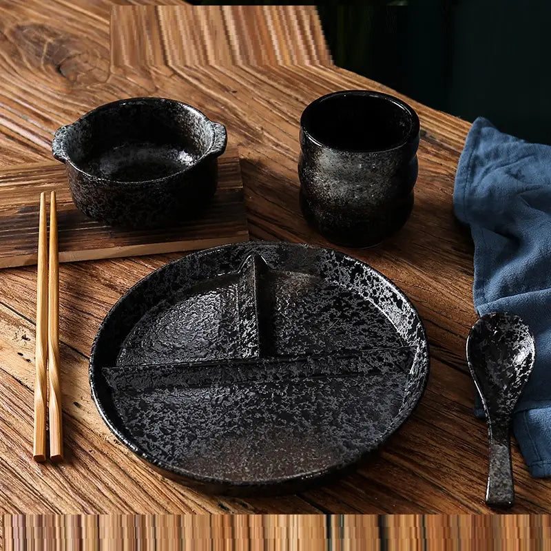 Assiette de dîner noire en céramique à mouchetures avec séparateur central, conçue pour le contrôle des portions dans un ensemble d’assiette de dîner divisée.