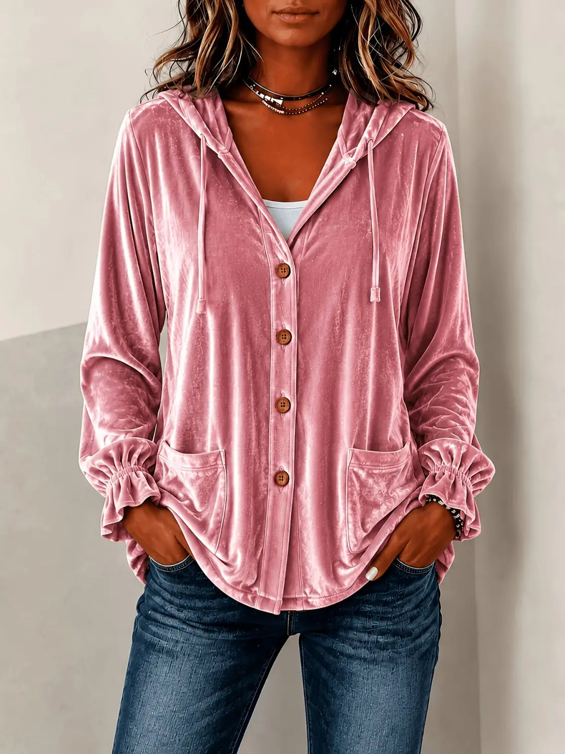 Un abrigo con capucha de terciopelo rosa suave, con botones de madera y puños con volantes.
