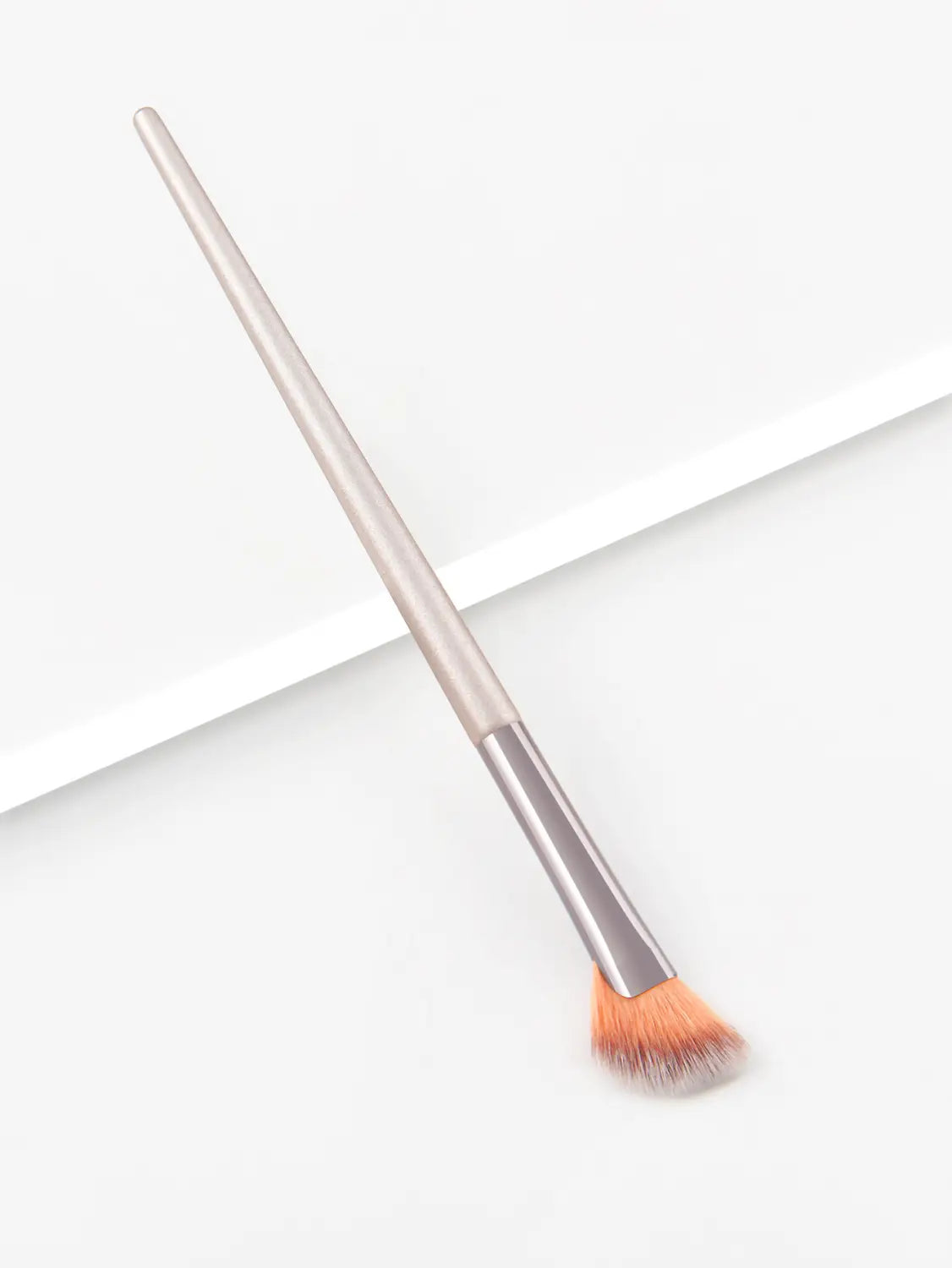 A sleek metallic-finished finger belly makeup brush with a tapered handle and soft orange-tipped bristles designed as a professional contour tool.
