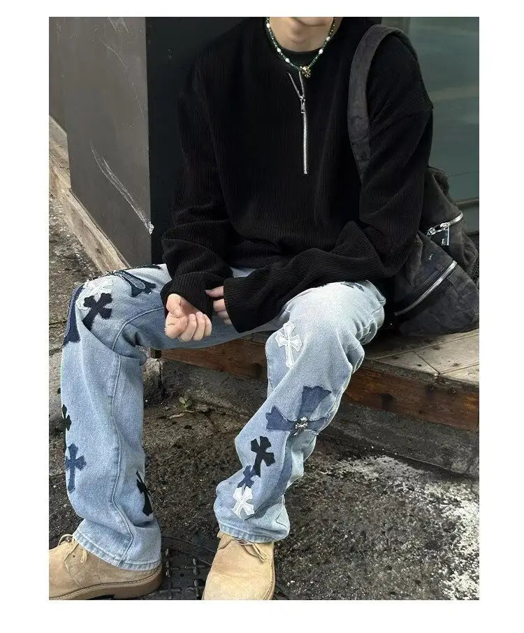 Sudadera tipo jersey acanalada de media cremallera para hombre, mostrada con jeans de mezclilla de lavado claro que presentan parches cruzados en negro y blanco.