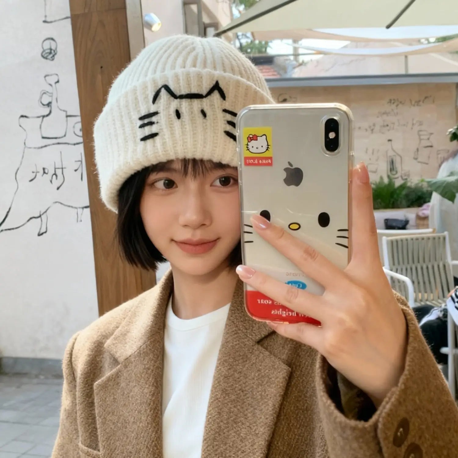 White knitted beanie hat with black cat face embroidery showcasing a soft and warm winter accessory.