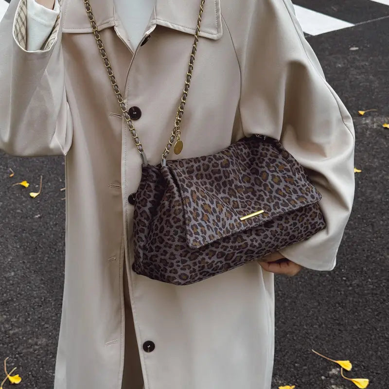 Leopard print crossbody bag featuring a gold-tone chain strap and flap closure in a stylish animal print design.