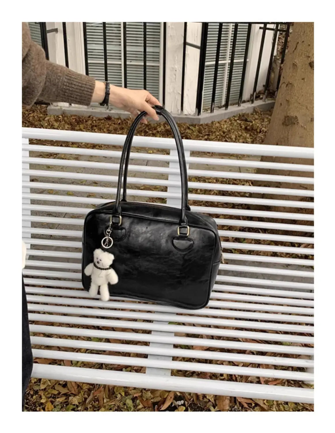 Black glossy leather large capacity shoulder bag with white teddy bear charm hanging from the handle.
