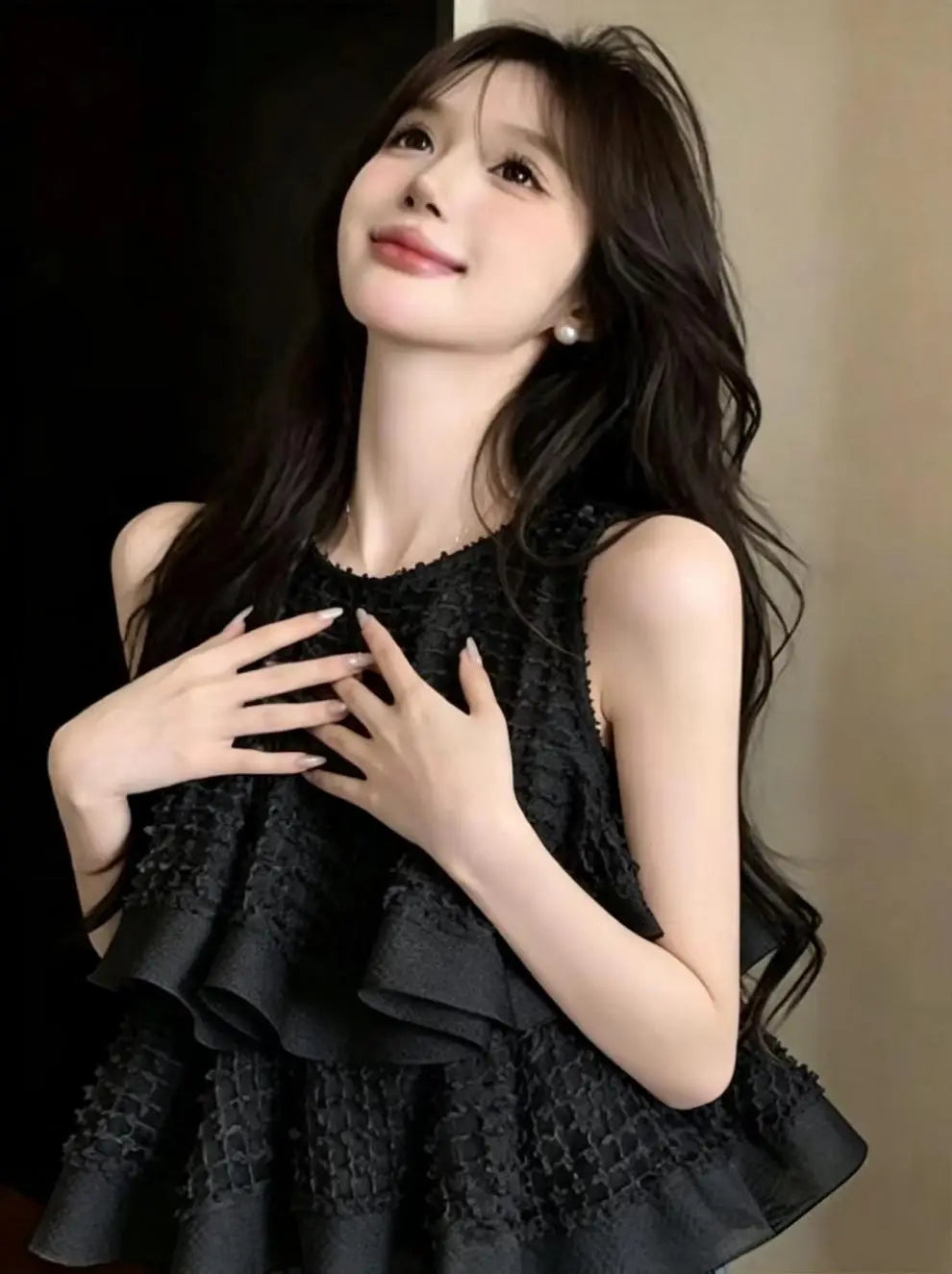 Blusa negra sin mangas con volante fruncido que presenta niveles de volante en capas y tejido con textura, adecuada para un uso casual con estilo.