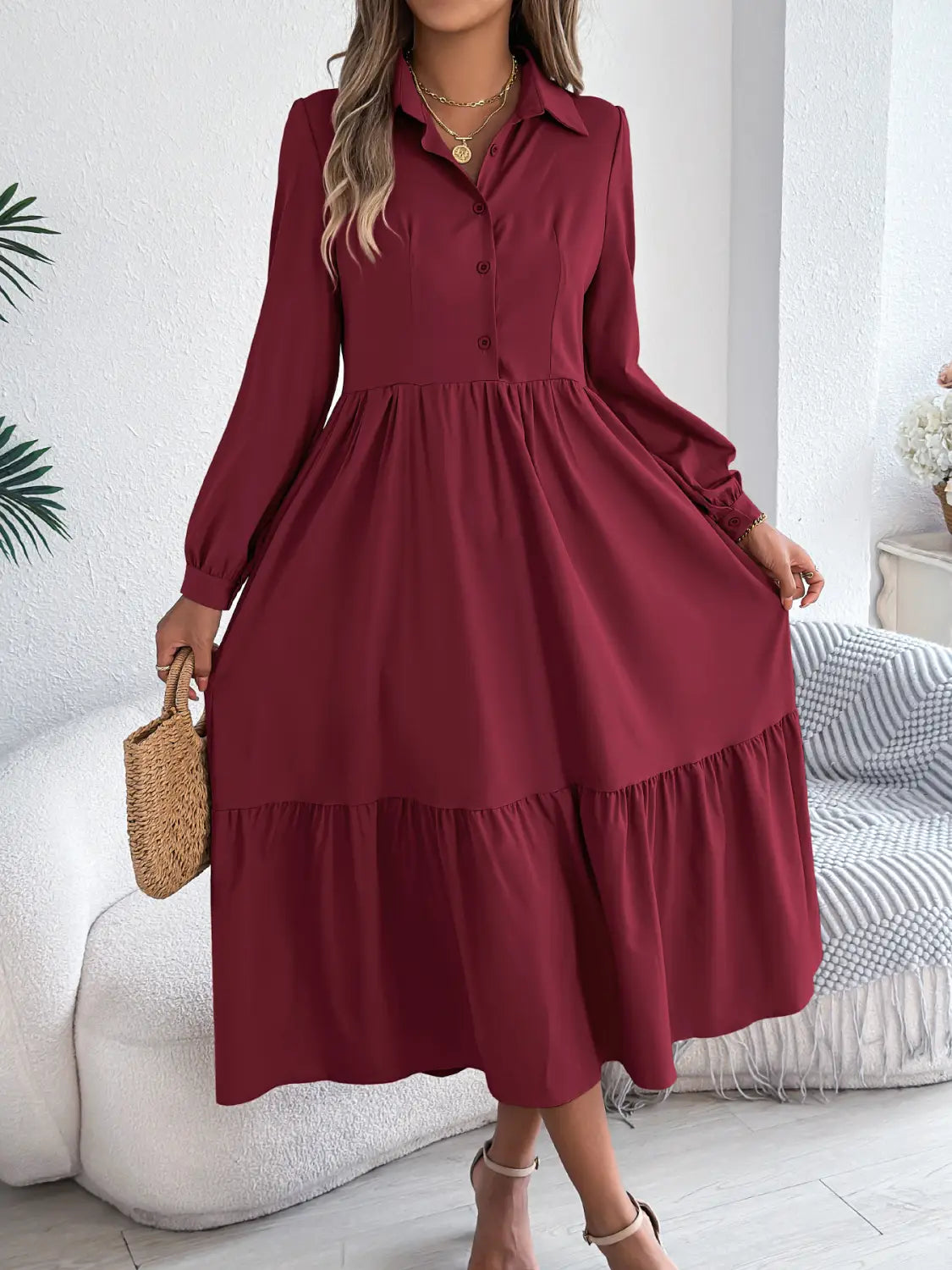 A women’s long sleeve tiered button down midi dress in burgundy with subtle ruffles and a flowing skirt.