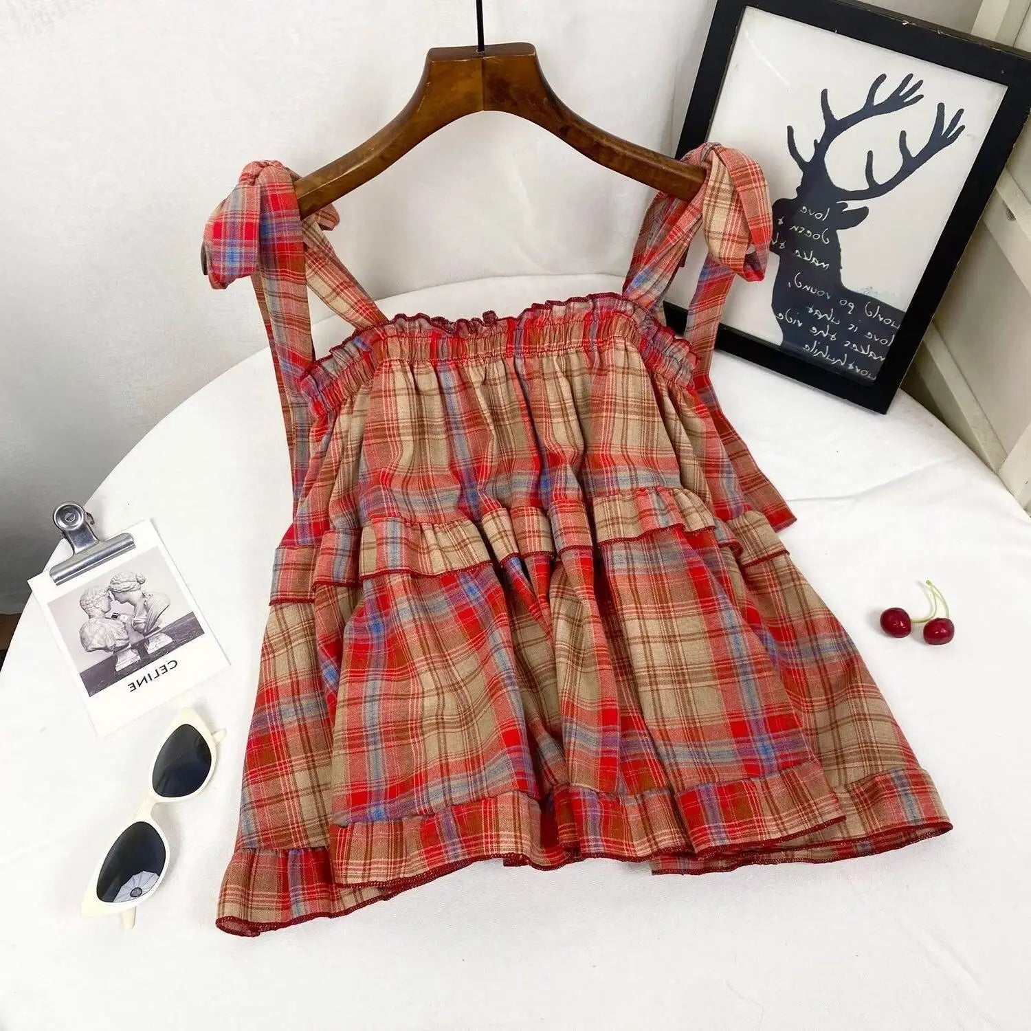 A red beige and blue plaid tiered dress with tied shoulder straps in a bow strap top design.
