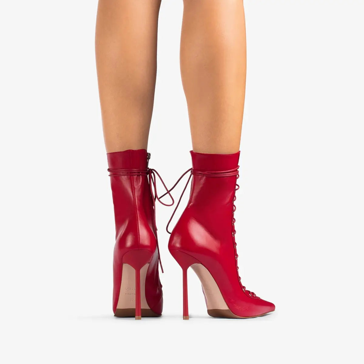 Des bottines à lacets en cuir verni rouge vif, à talons hauts fins, et des détails de laçage assortis au style des sandales à talon aiguille haut à bout pointu en mesh à lacets