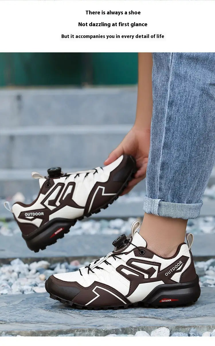 White and brown lightweight off-road breathable hiking shoe with black laces, a distinctive logo on the side, and an adjustable strap system designed for outdoor use.