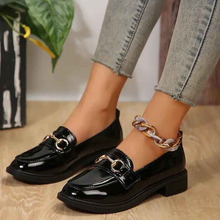 Schwarze Lackleder-Damenloafer mit goldfarbenem Pferdebit-Detailing und einem klobigen Knöchelriemen mit Kettenstruktur sowie mit einem klobigen Absatz.