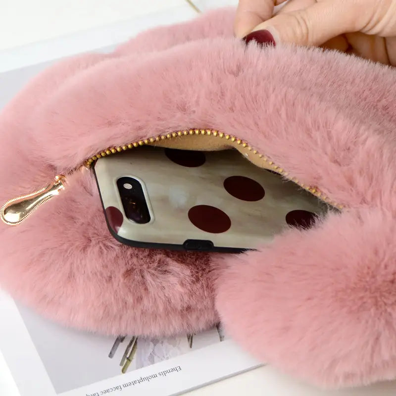 plush faux fur heart shaped crossbody bag in pink with a gold chain and a phone case featuring pink faux fur and a gold zipper.