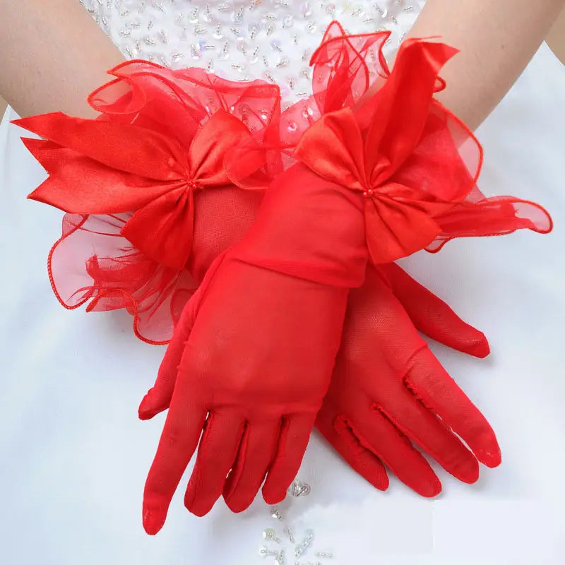Elegant black lace and satin bow evening gloves featuring red satin material with sheer organza bows at the wrists.