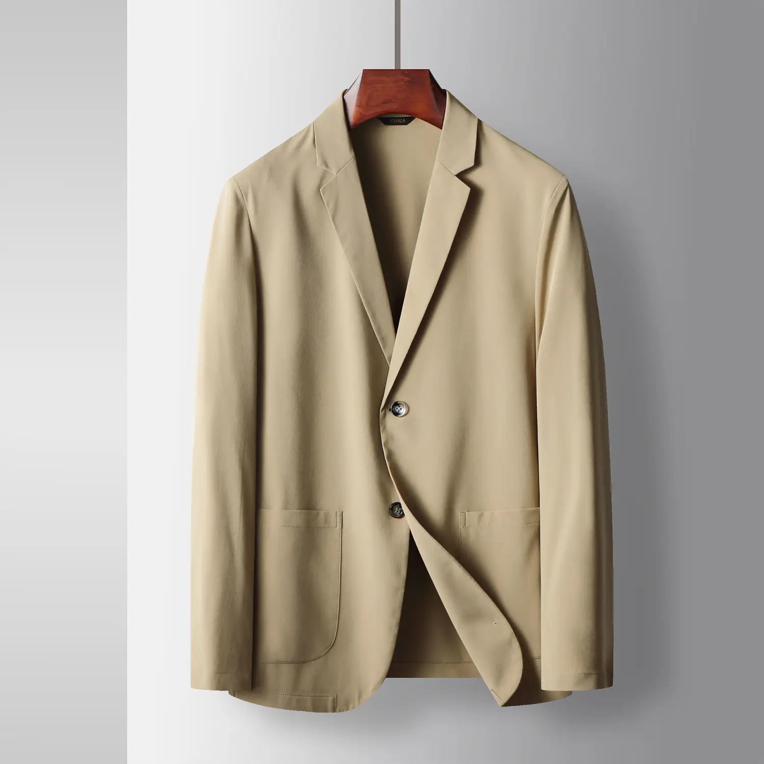 Beige Herren-Leichtgewicht-Stretch-Anzugjacke gegen Falten, einreihig, mit zwei Frontknöpfen und Klappentaschen, an einem Holzkleiderbügel hängend.