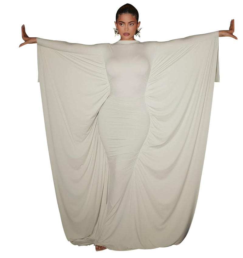 A flowing off-white satin asymmetrical maxi dress with form-fitting silhouette and wide dramatic batwing sleeves draping elegantly from the shoulders.
