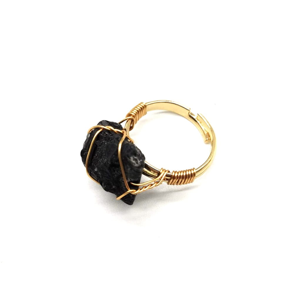 A handcrafted gold wire wrapped adjustable ring featuring a raw black obsidian gemstone.