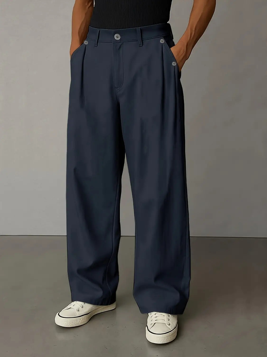 Des pantalons décontractés plissés à jambes larges bleu marine foncé pour hommes, présentant un design minimaliste épuré avec de discrets détails de boutons à la ceinture.