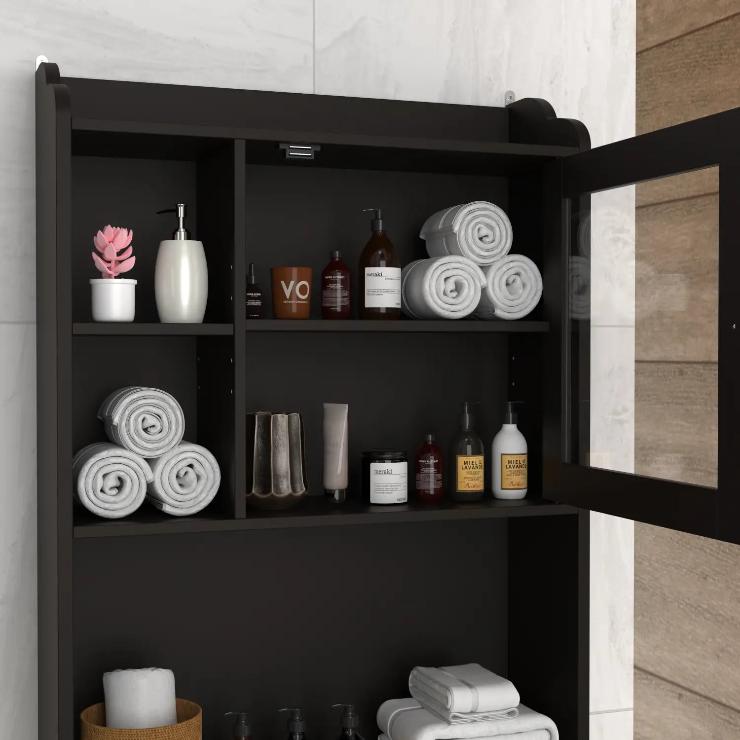 Black espresso wood over the toilet bathroom storage cabinet with glass door and multiple shelves holding rolled towels bottles and a small pink plant.