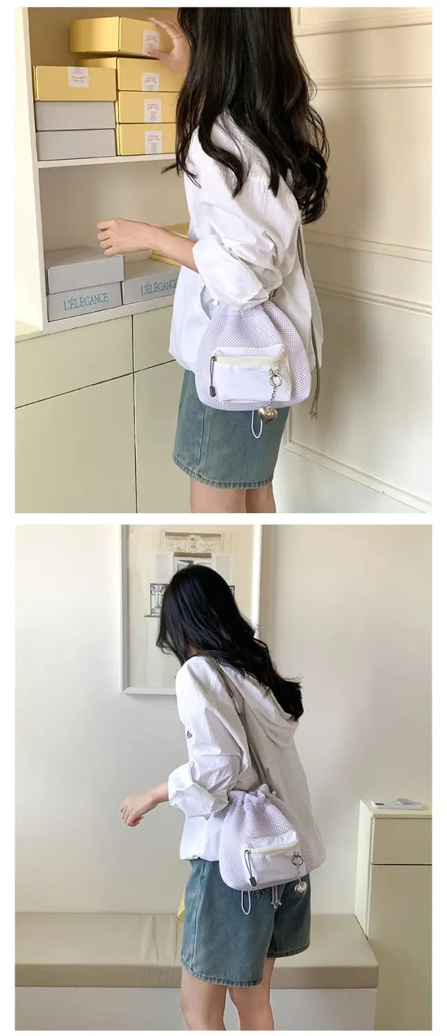 White drawstring crossbody bucket bag with subtle textured pattern and metallic hardware accents featured as a mini pink mesh drawstring bucket bag with heart charm.