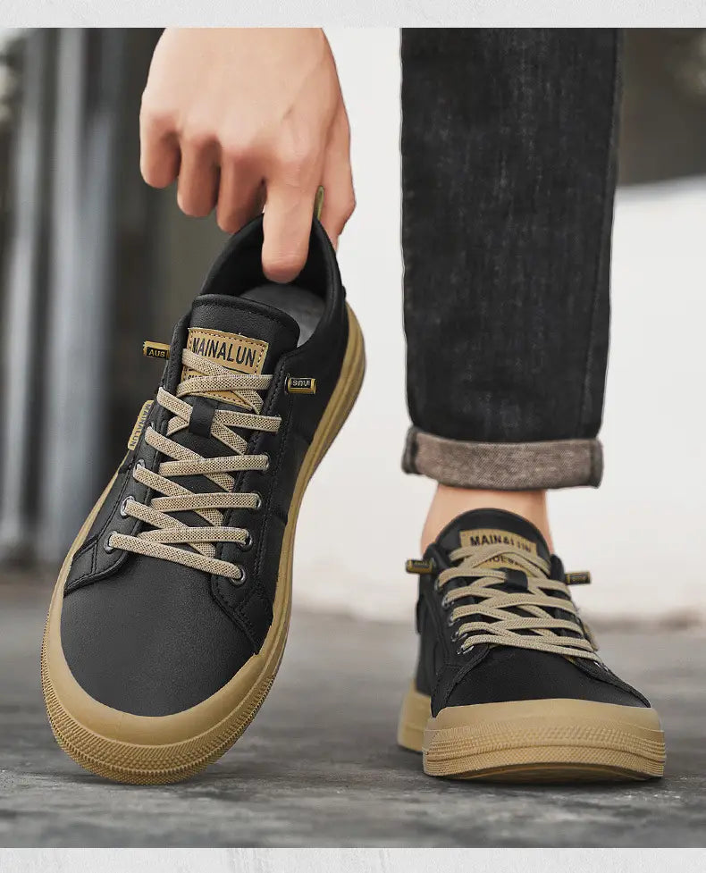 Men’s white minimalist leather casual sneakers shown in black canvas with tan rubber soles and laces featuring a mainalun brand label on the tongue.