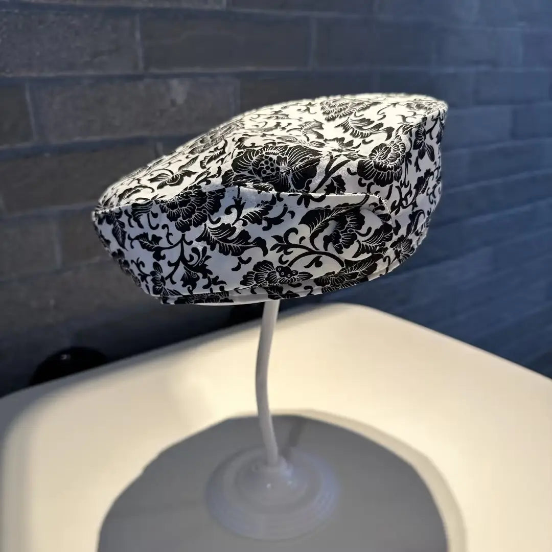Printed Korean style fashion cap in black and white floral patterned fabric displayed on a stand