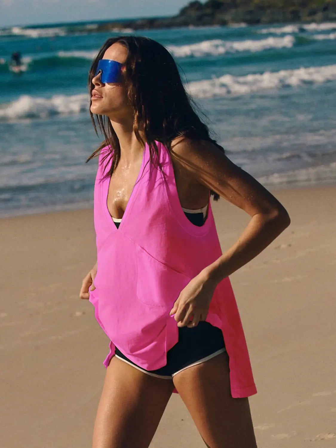 A vibrant pink sleeveless cotton wrap vest top with a deep v-neckline and side ties designed as a relaxed beach cover-up.