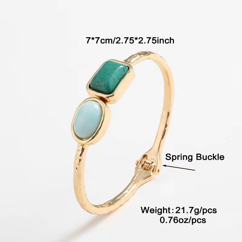 Vintage hammered gold bangle featuring a textured, hammered metal band with two rectangular turquoise stones and a spring buckle closure.