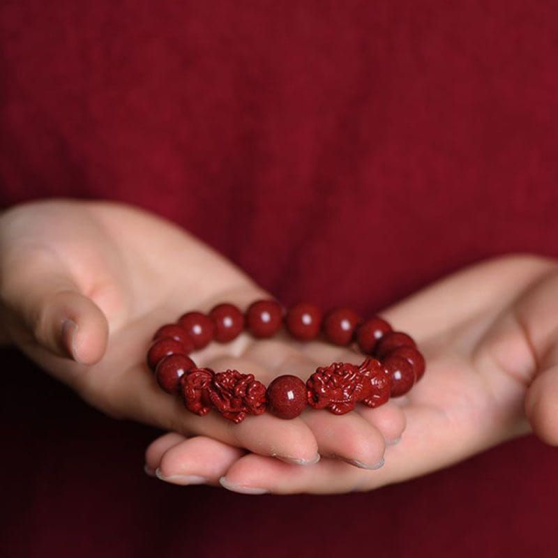 Hand carved purple gold cinnabar double pixiu bracelet featuring rich crimson red polished beads with intricately carved floral and dragon motifs.
