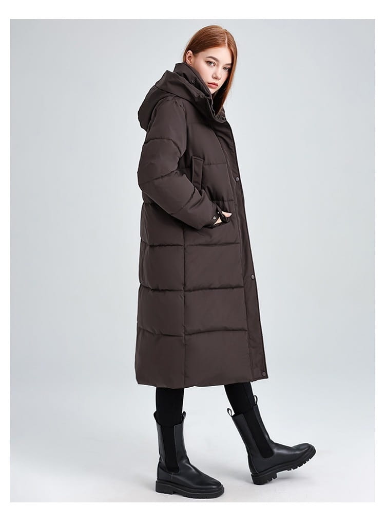 Manteau long matelassé à capuche pour femmes en brun foncé, avec fermeture boutonnée à l’avant.
