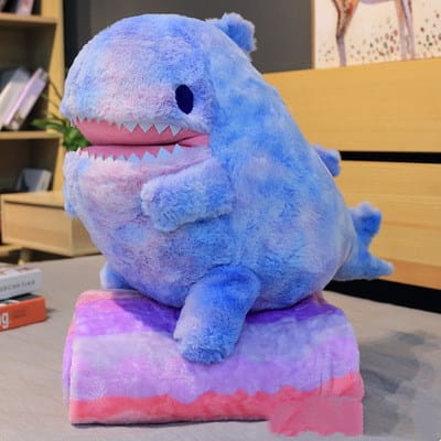 青いサメがグラデーションの紫とピンクの腹を持ち、同系色のパステルカラーのクッションの上に座った、ぬいぐるみの恐竜タイダイグラデーション柄の60cmドール