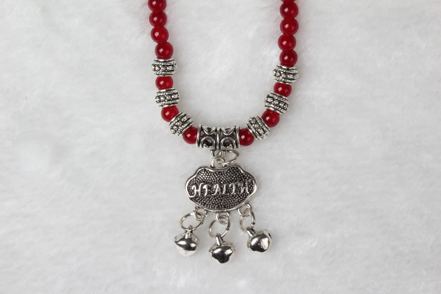 a red agate good luck bracelet featuring red beads with a silver-toned health charm and dangling bells for protection and positive energy