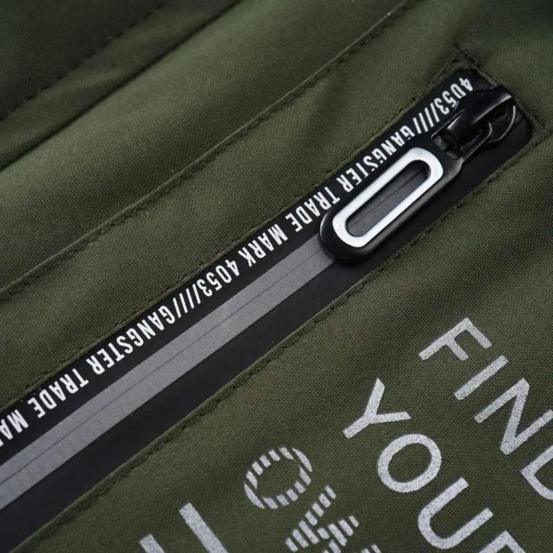 Olive green nylon backpack with black zipper pull and reflective stripe detailing paired with mens outdoor fleece hooded jacket casual shell coat.
