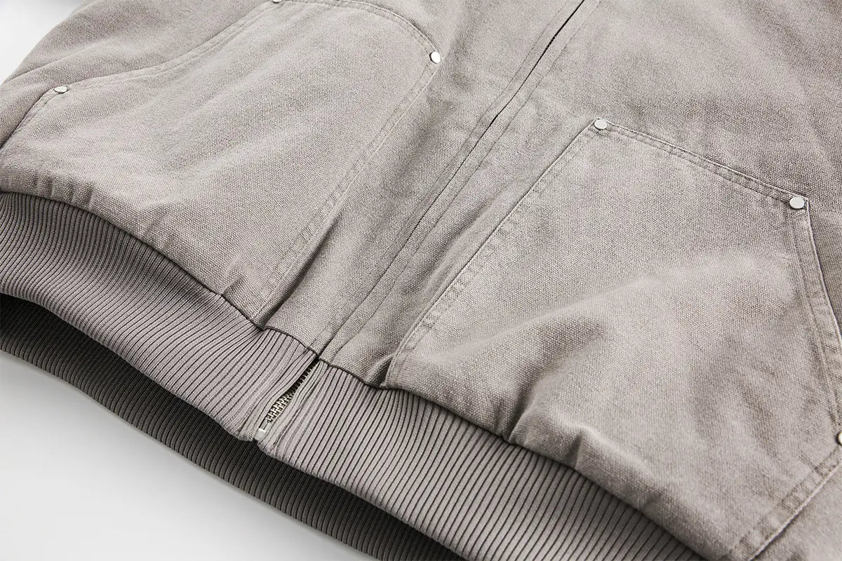 Chaqueta de pana gris con puños acanalados y detalles de botones con acabado plateado, como parte de un abrigo acolchado de invierno de algodón con forro de piel sintética para hombre y mujer.