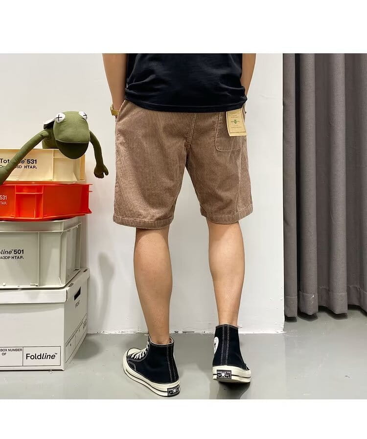 Herren-Retro-Cord-Sommer-Arbeitsbekleidung mit Kordelzug und kurzen Hosen in Braun mit einer Vorder...tasche und einem beigen Etikett am Bund.