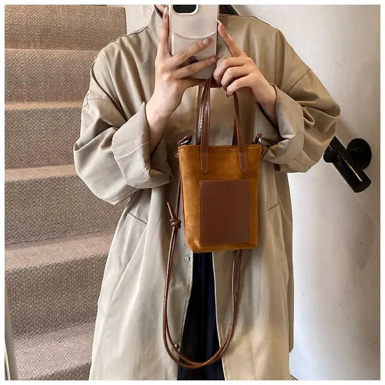 A tan suede mini tote bag with a contrasting brown leather patch and matching handles featured as a retro leopard print suede mini bucket crossbody bag.