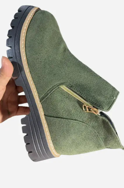 Botín de ante verde oliva con suela negra de goma gruesa y cremallera lateral en tono dorado, en un producto de botines de ante con cremallera lateral y suela gruesa.