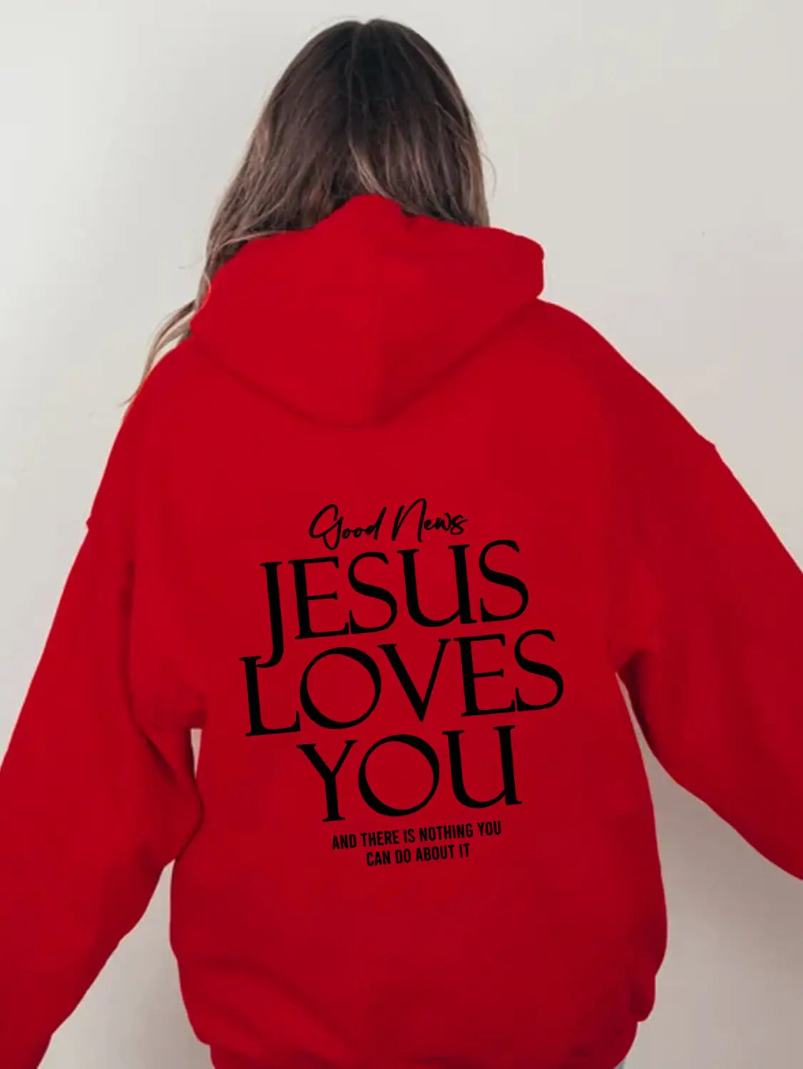 The back side of a vibrant red oversized streetwear hoodie features a kangaroo pocket and bold black text reading Jesus loves you with smaller matching script above and below.