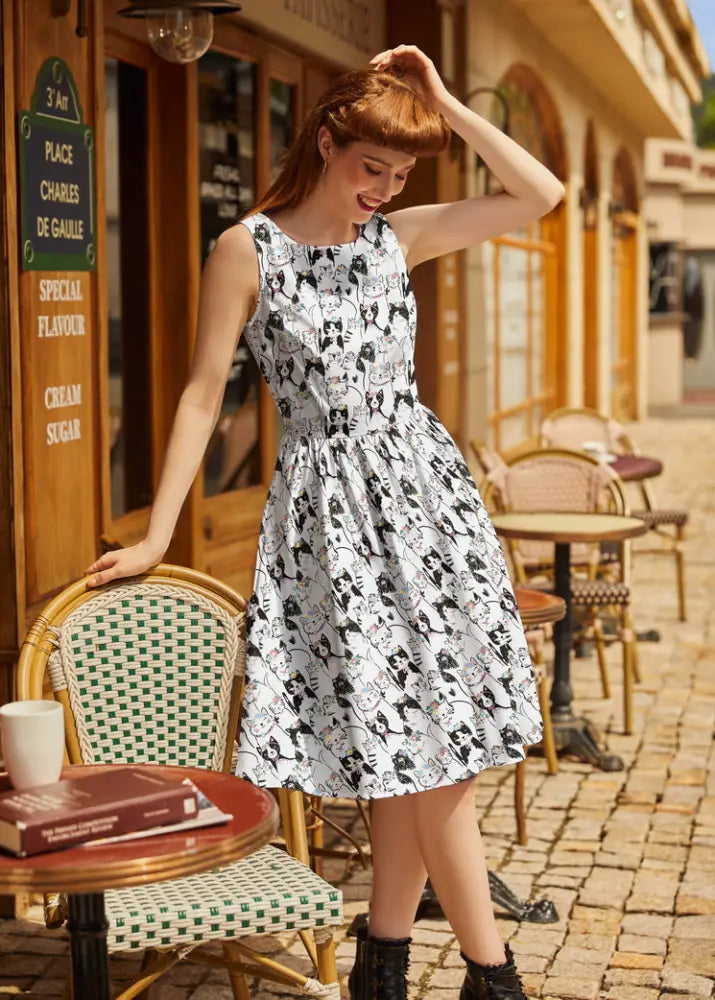 A fabulous felines vintage 1950s white cotton sleeveless dress with black cat print fitted waist and flared skirt