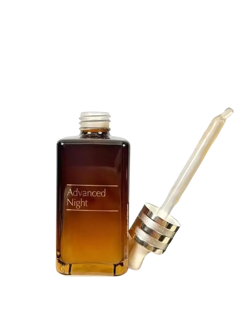 A sleek rectangular glass bottle with gradient amber advanced night care face serum 100ml and matching dropper