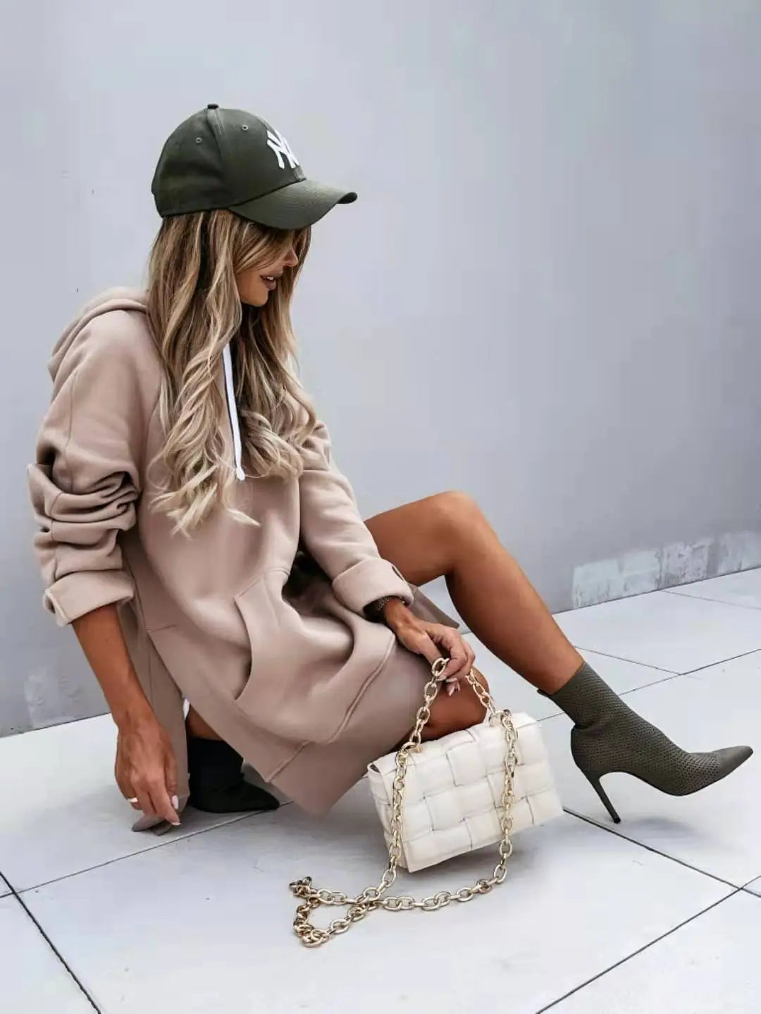 white quilted chain strap handbag displayed with an oversized mid length hooded sweatshirt dress with pockets
