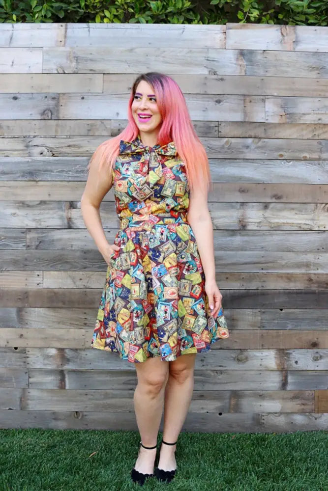 A sleeveless knee-length dress in 2x featuring a vibrant vintage cereal box collage print in assorted colors