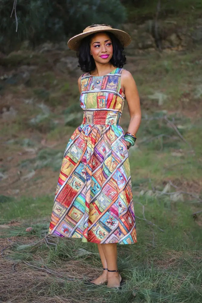 A vibrant sleeveless cotton midi dress with a colorful patchwork of vintage book covers titled Fairytales Bibliophile