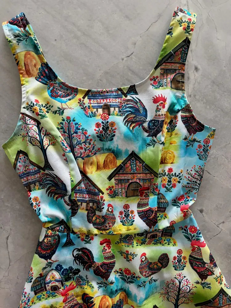 A vibrant sleeveless skater dress with colorful folk art farm print on light green and white background featuring pockets