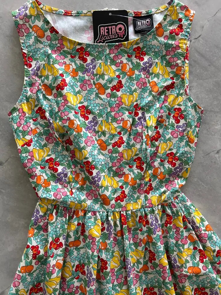 A vibrant sleeveless cotton retro midi dress with colorful fruit prints and pockets on a white background