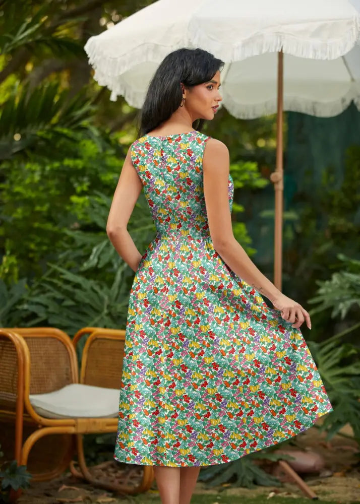 A vibrant green cotton retro midi dress with colorful fruit motifs sleeveless fitted at the waist with pockets
