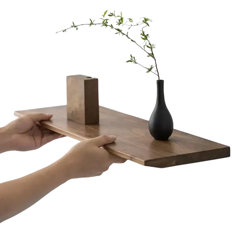 Dark matte black ceramic vase with slender neck holding green branch on wooden shelves live edge wall farmhouse wooden