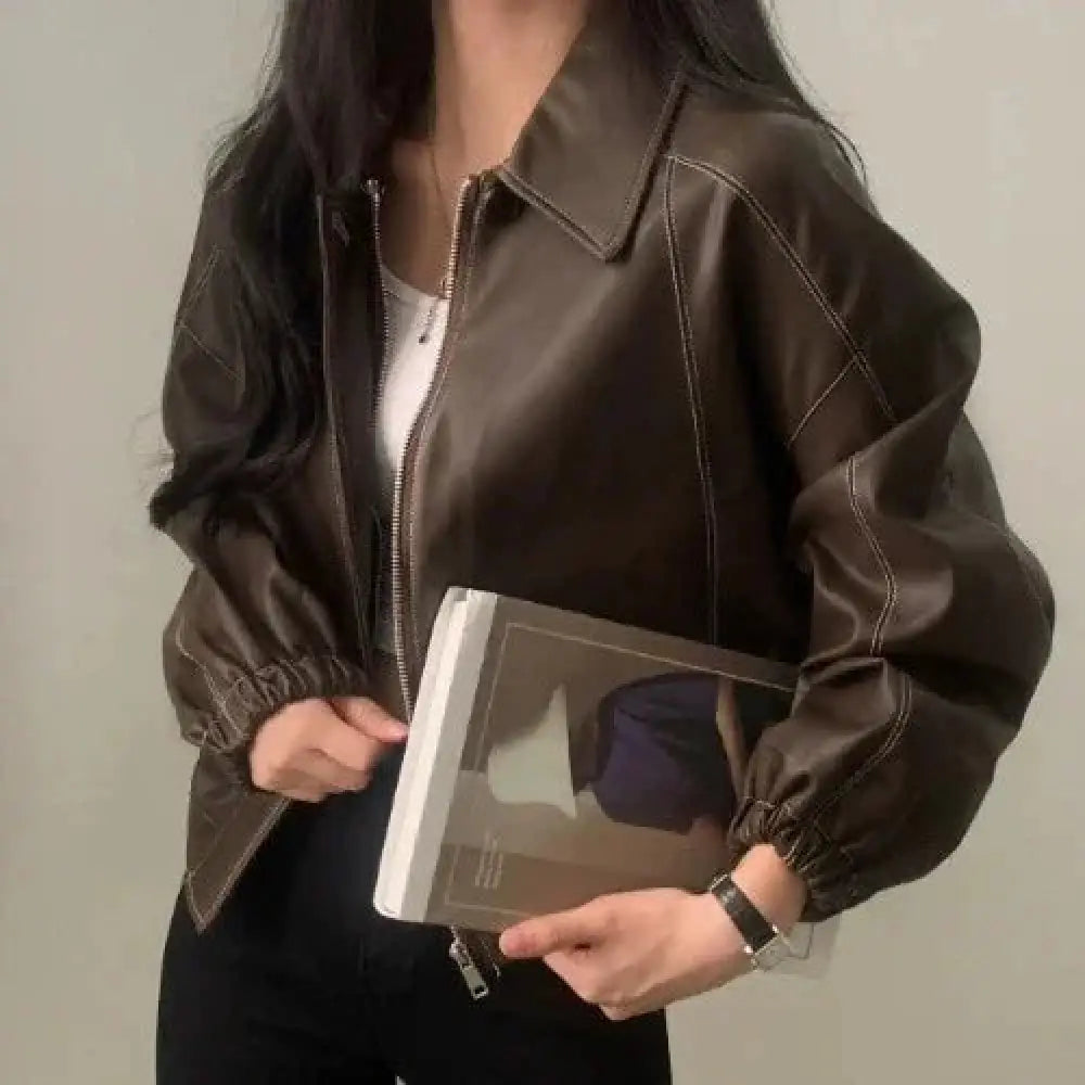 Brown faux leather bomber jacket with contrasting white stitching and elastic cuffs shown from the back side