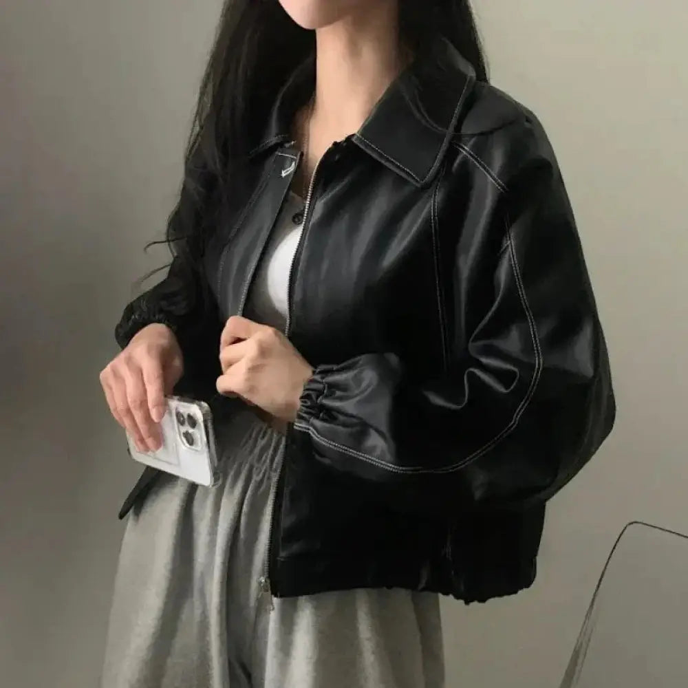 Black faux leather bomber jacket with contrast white stitching and elastic cuffs shown from the back side