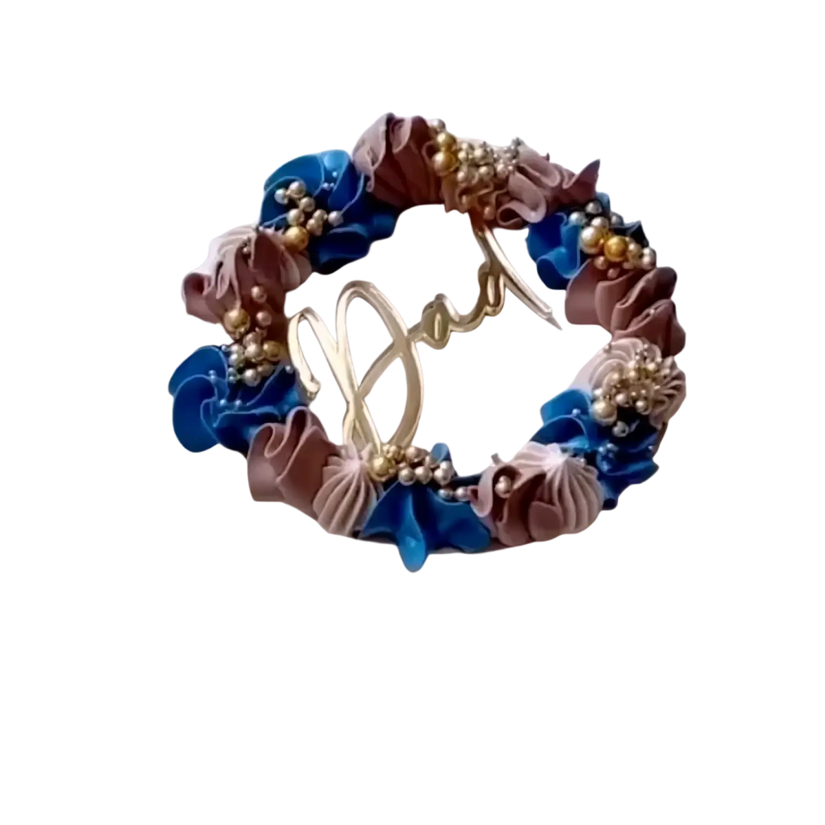 A delicate round Father’s Day dad cake topper in black and gold acrylic with blue mauve frosting flowers and gold beads