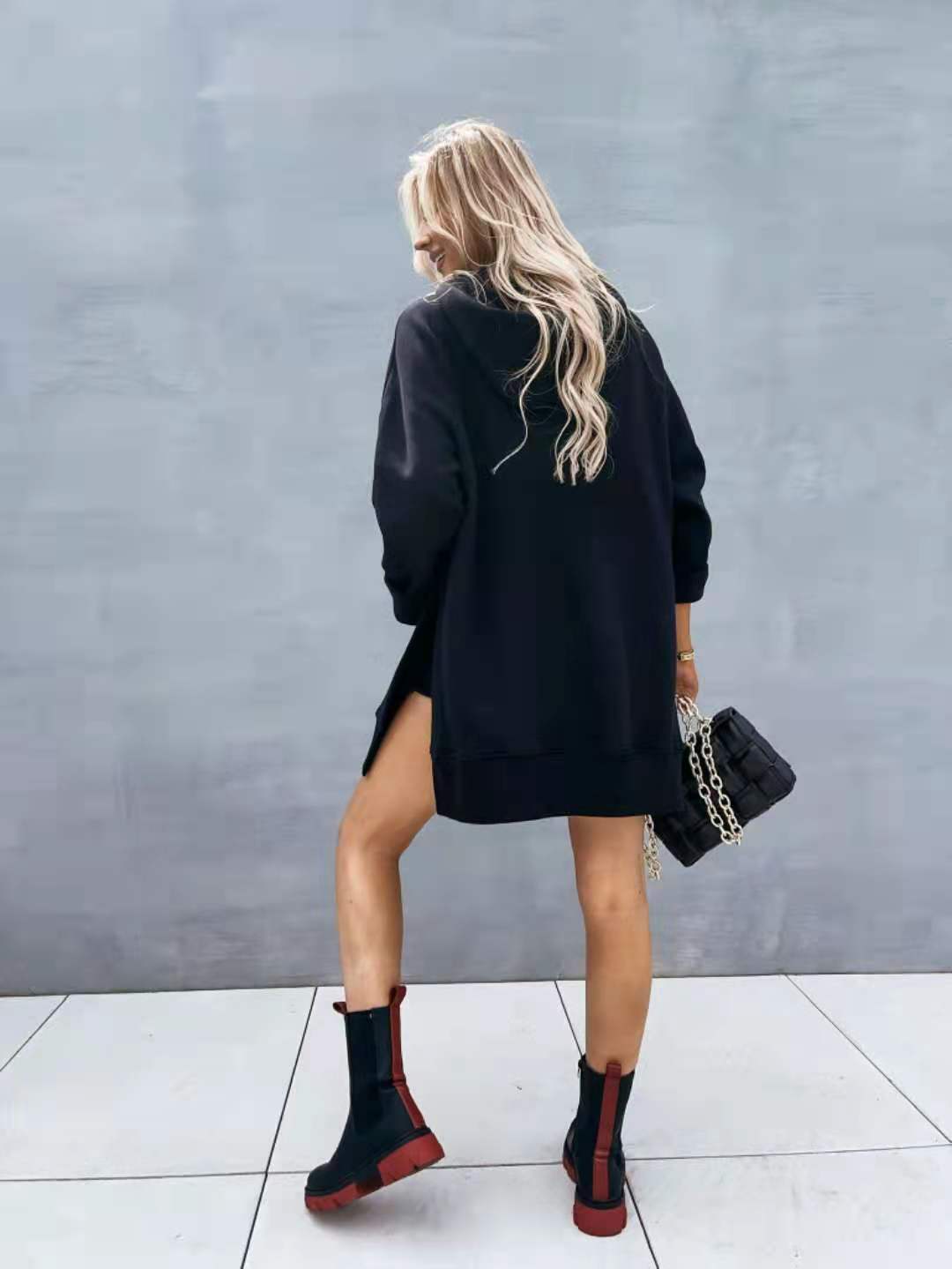 Black quilted leather handbag with silver-toned chain-link hardware paired with an oversized mid length hooded sweatshirt dress with pockets.