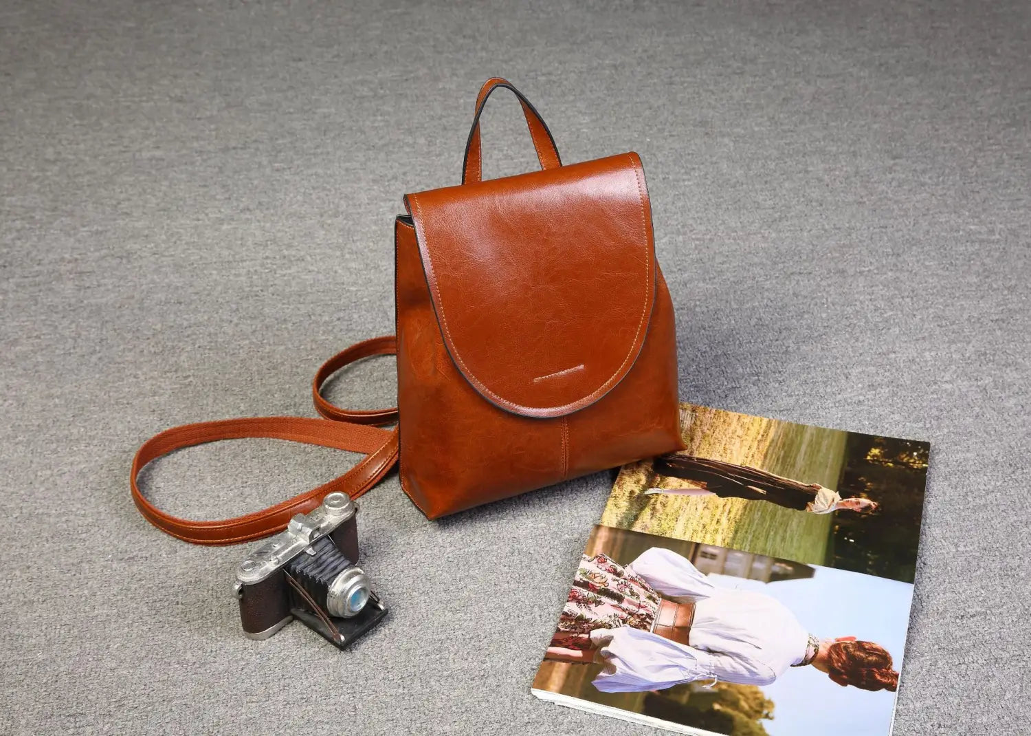 Una mochila bandolera de cuero marrón cálido con un diseño sencillo y elegante y una correa de hombro a juego, adecuada para el uso en moda retro.